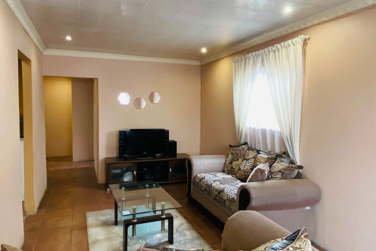 A living room featuring tiled flooring, coved ceilings, and recessed lighting, providing a functional and neutral space.