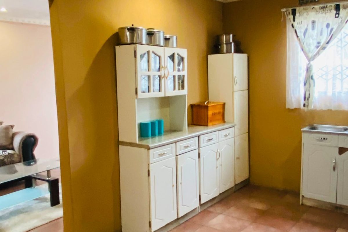 A functional kitchen featuring built-in cabinetry, tiled flooring, and a sink, offering potential for modernization and aesthetic updates.