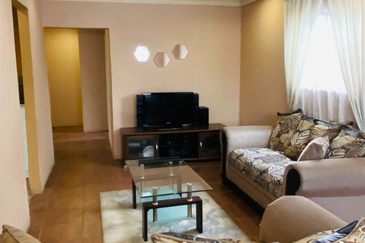 A comfortable living room featuring tiled flooring, coved ceiling details, and recessed lighting, providing a functional and neutral space for relaxation.
