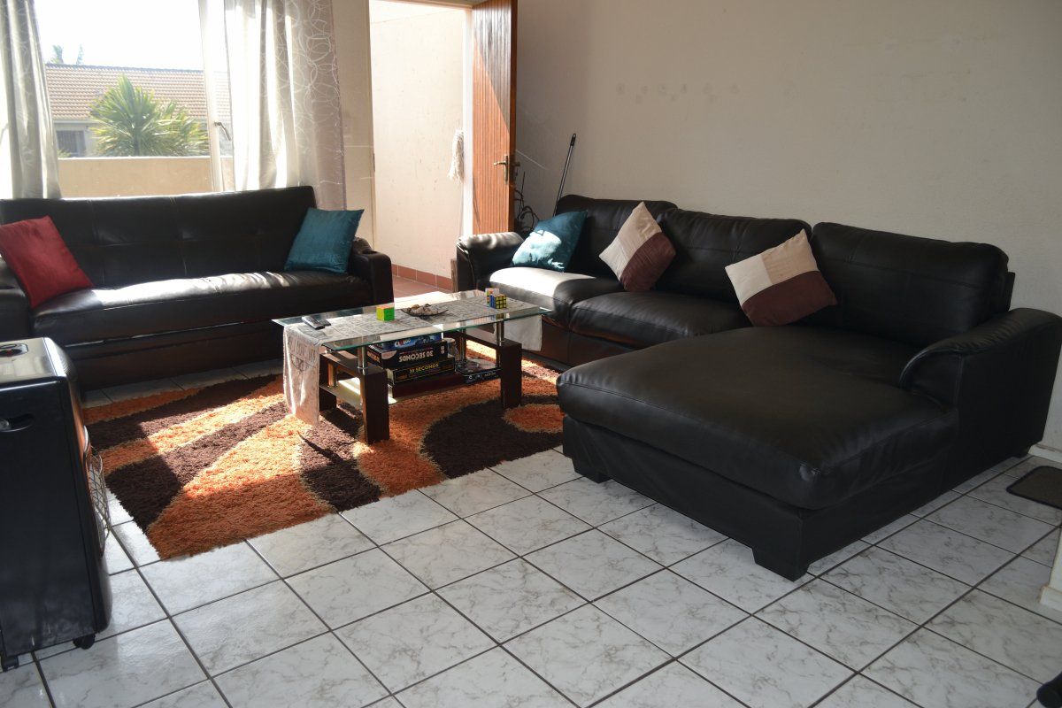 A living room area featuring tiled flooring and access to an outdoor patio through a sliding glass door.