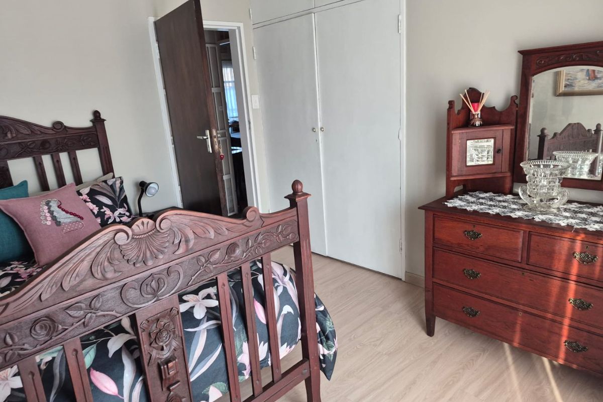 A bedroom featuring light-toned laminate flooring and built-in storage cupboards with white doors.