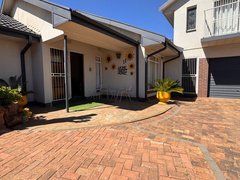 Front elevation of a multi-level house featuring a paved driveway, covered entrance area, security gates, and an integrated garage.