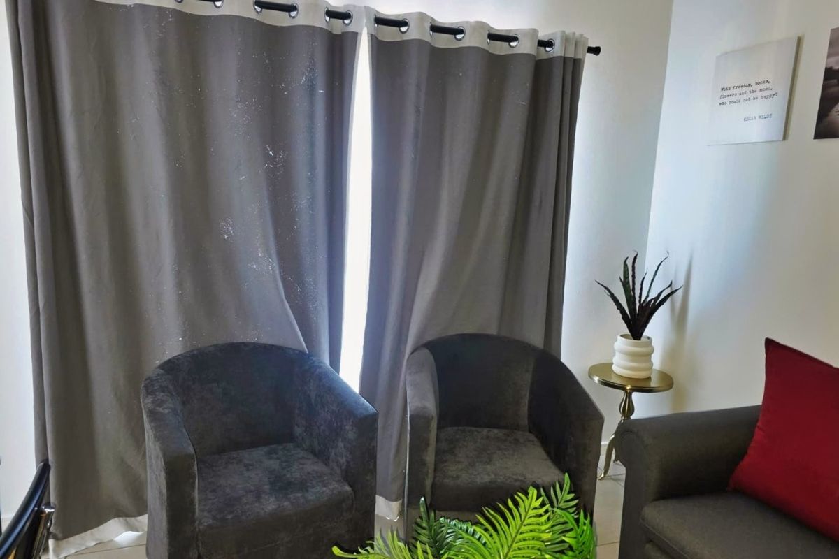 A living room area featuring tiled flooring and window treatments, providing a functional space for relaxation.