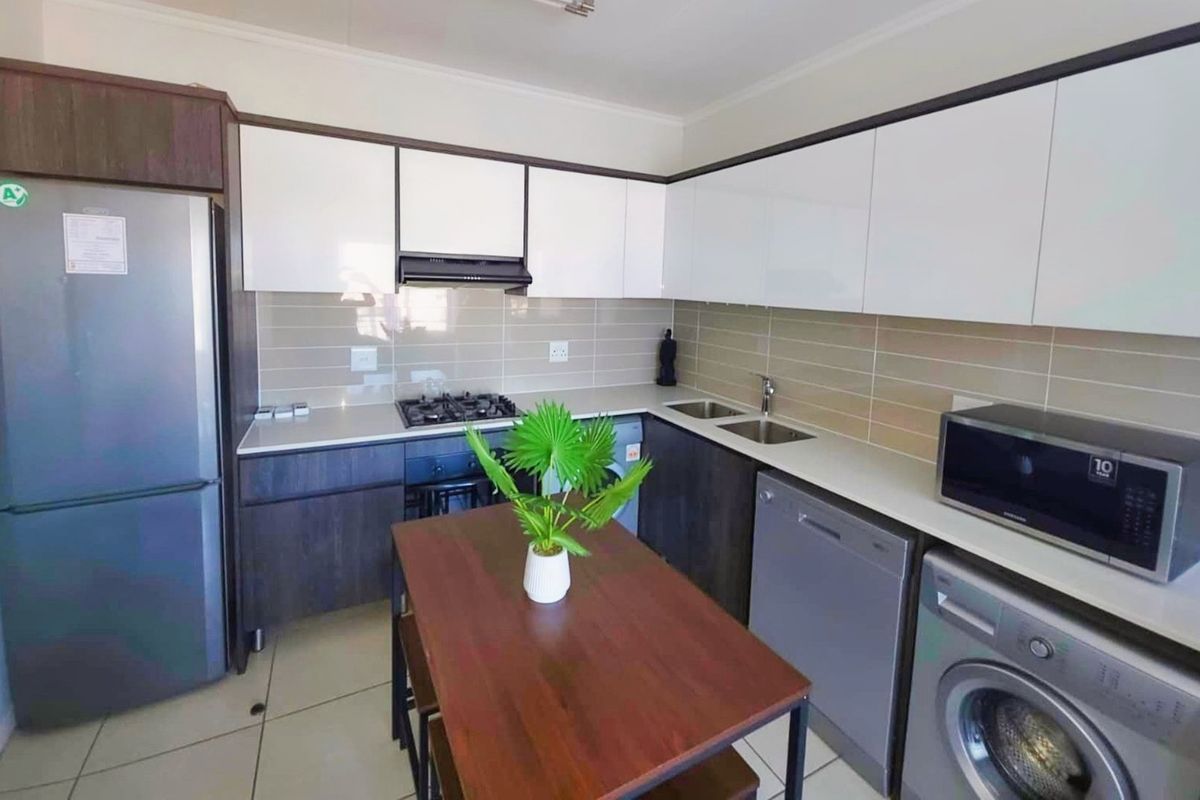 Modern kitchen featuring sleek two-tone cabinetry, gas hob, extractor fan, and integrated space for laundry and dishwashing appliances.