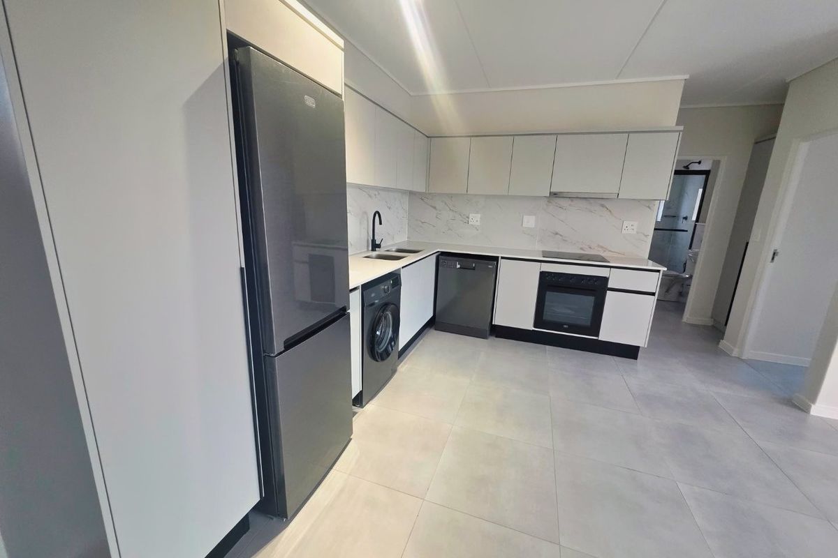 Modern kitchen featuring sleek white cabinetry, marble-look splashback, integrated oven, hob, and tiled flooring in a clean, contemporary layout.