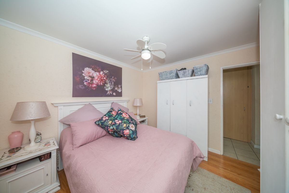 A cozy bedroom featuring laminate flooring, a ceiling fan, and a built-in wardrobe, offering a comfortable and functional living space.