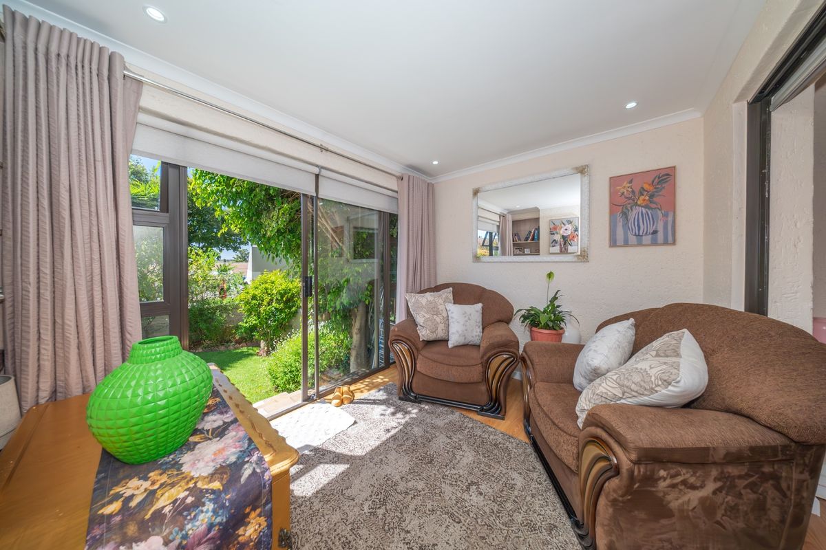 A cozy living room featuring laminate flooring, recessed lighting, and large sliding glass doors that provide direct access to the garden.