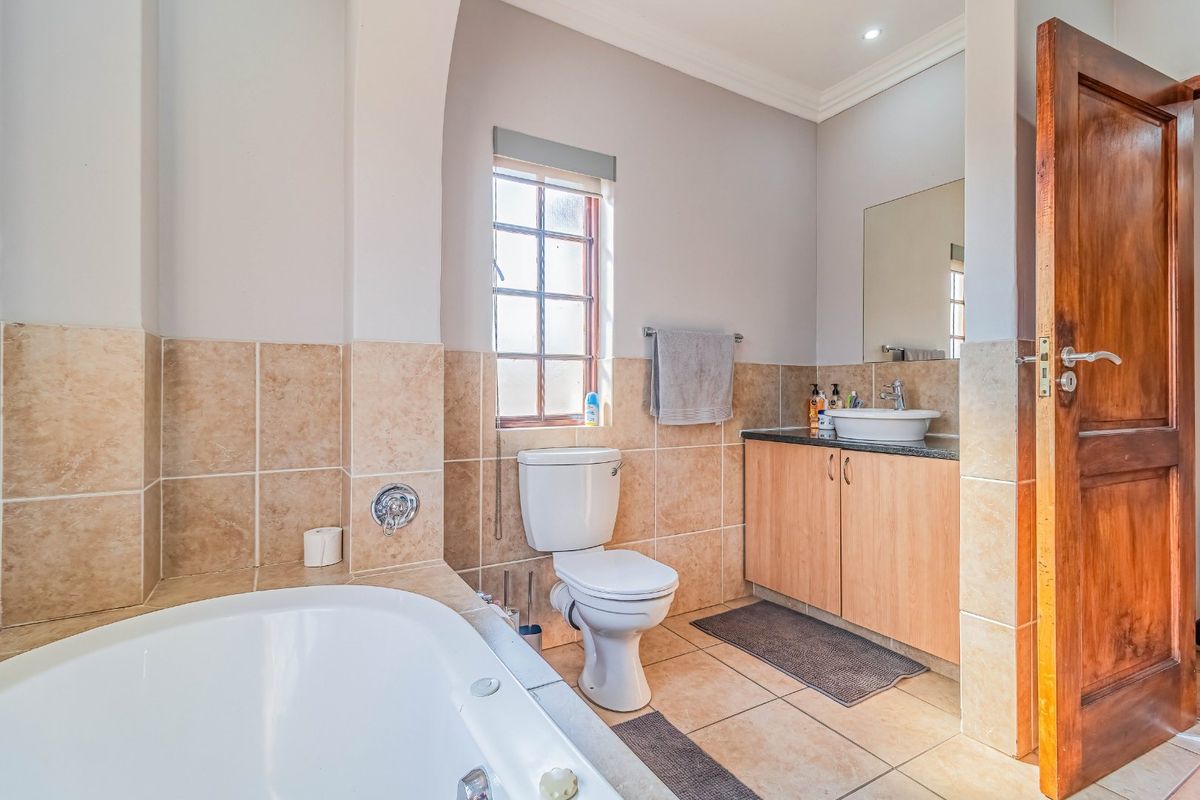 A functional bathroom featuring a built-in vanity with a vessel sink, a toilet, and a bathtub with tiled wall surrounds.