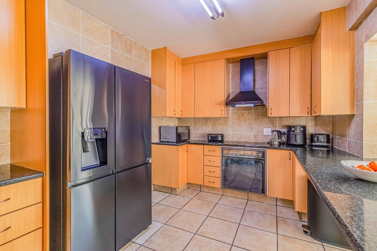 A functional kitchen featuring light wood cabinetry, granite countertops, tiled backsplash, and built-in oven with an extractor fan.