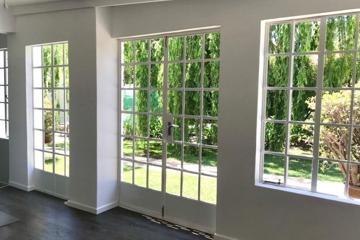 Bright living area featuring large grid-pattern windows and french doors that provide ample natural light and direct access to the garden.