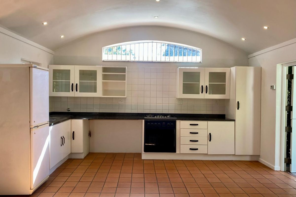 A spacious kitchen featuring a vaulted ceiling, tiled flooring, built-in cabinetry, and a built-in oven with a gas hob.