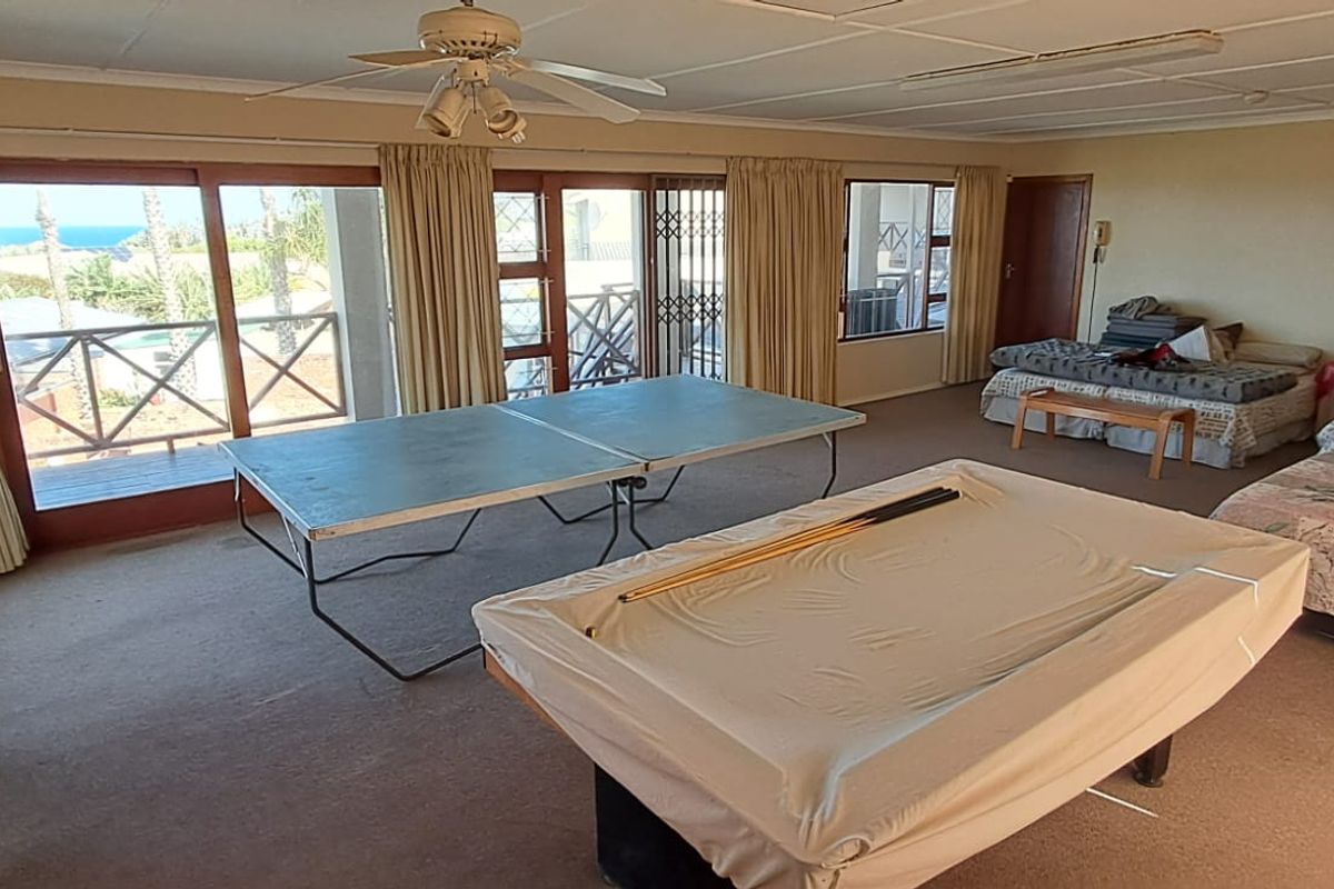 Spacious living area featuring large sliding glass doors with access to an outdoor balcony, ceiling fan, and neutral carpeted flooring.