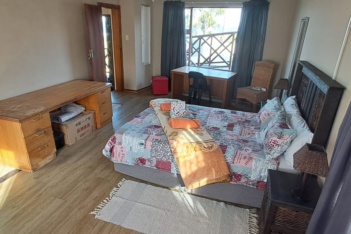A spacious bedroom featuring laminate flooring, a built-in cupboard, and a sliding door providing access to an outdoor area.
