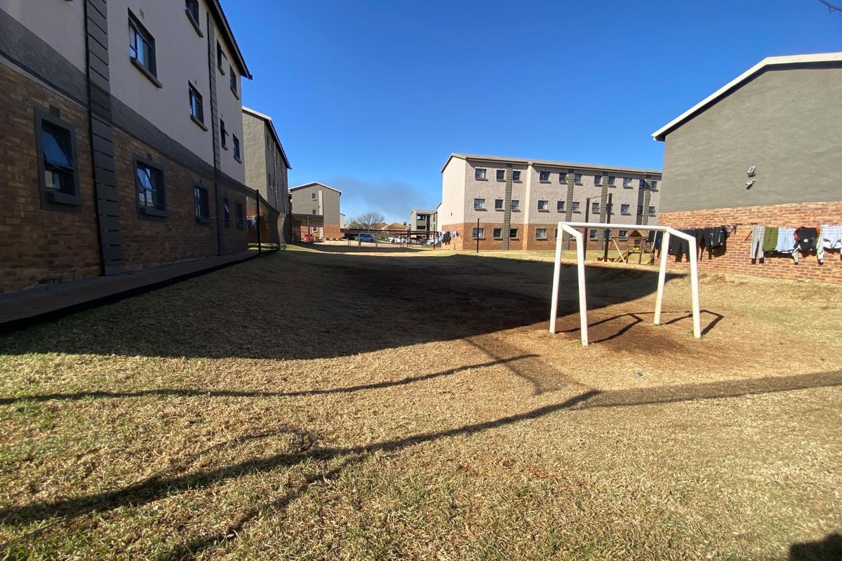 A view of the communal outdoor space between apartment blocks, featuring a lawn area and a fixed soccer goal post.