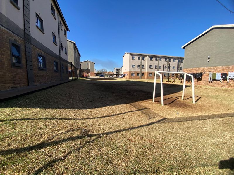 A view of the communal outdoor space between apartment blocks, featuring a lawn area and a fixed soccer goal post.