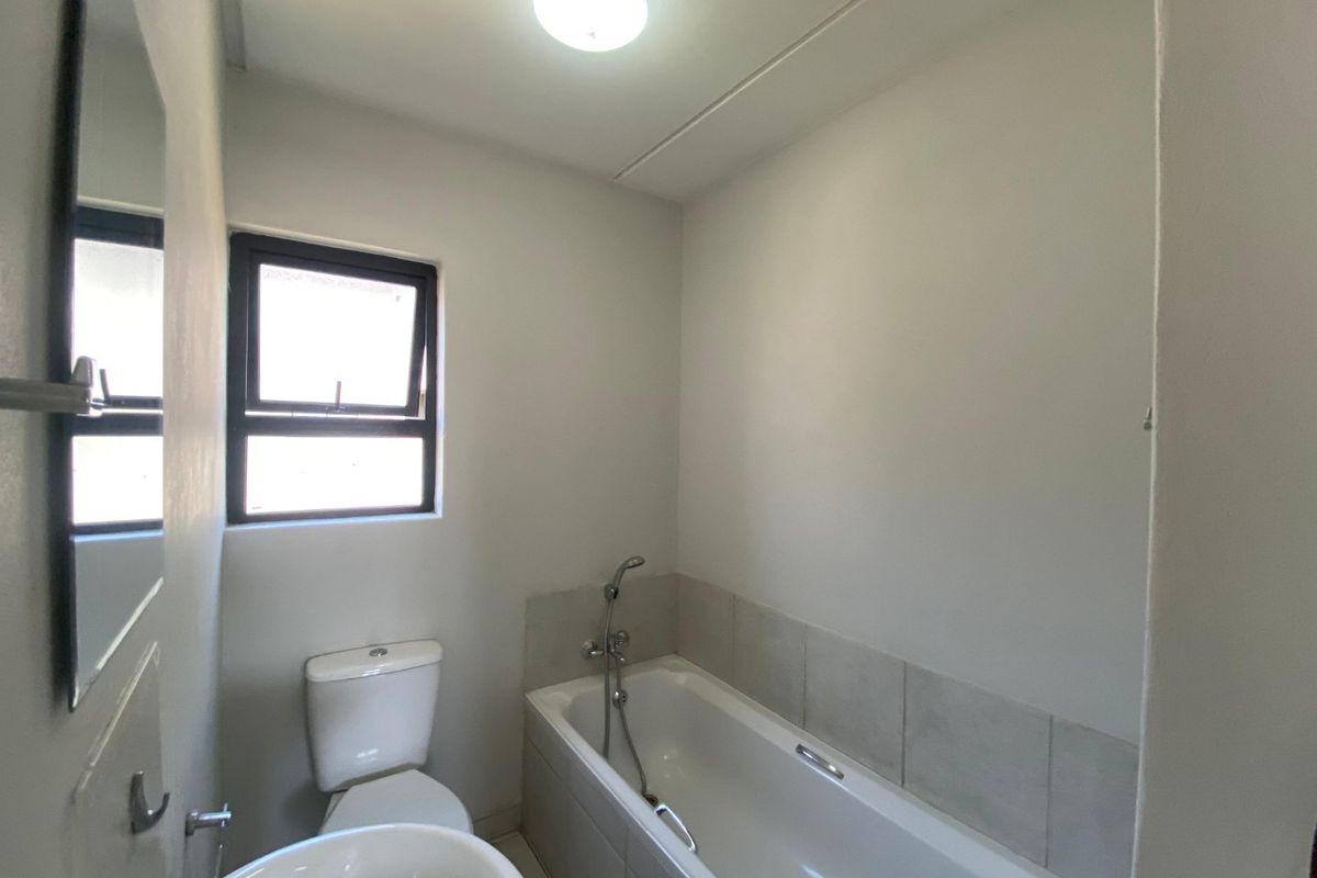 A clean and functional bathroom featuring a bathtub with a handheld shower mixer, a pedestal basin, and a toilet.