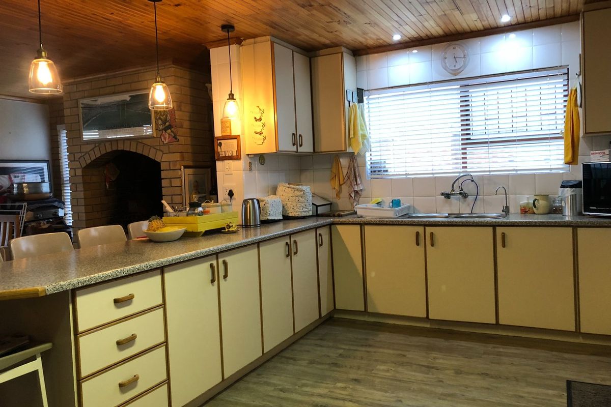 A functional kitchen featuring laminate cabinetry, a double bowl sink, and a distinctive timber ceiling, adjacent to a brick fireplace feature.