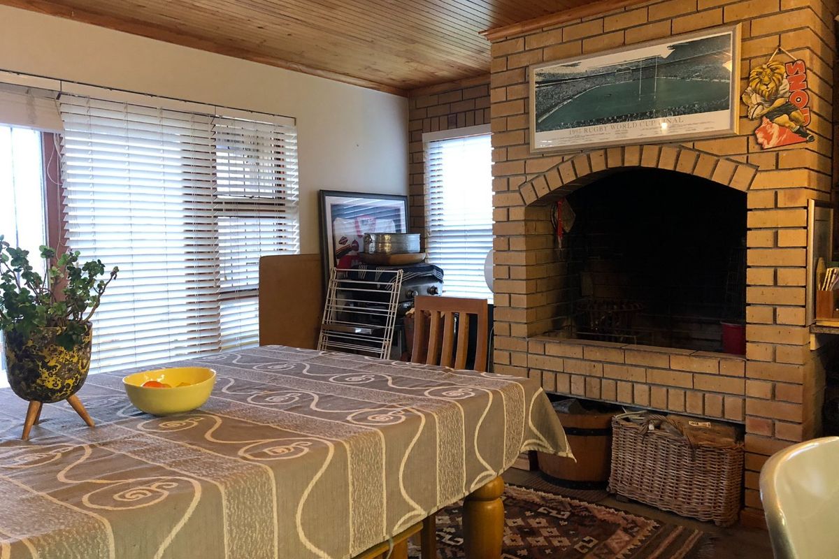 A living room featuring a prominent brick fireplace and timber-clad ceiling, providing a rustic and cozy atmosphere.