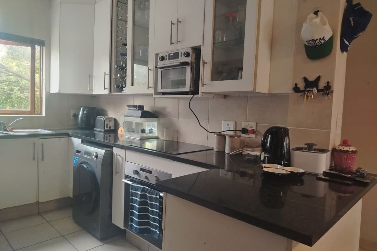 A functional kitchen featuring white cabinetry, dark granite countertops, built-in oven and microwave, and tiled flooring with a window for natural light.