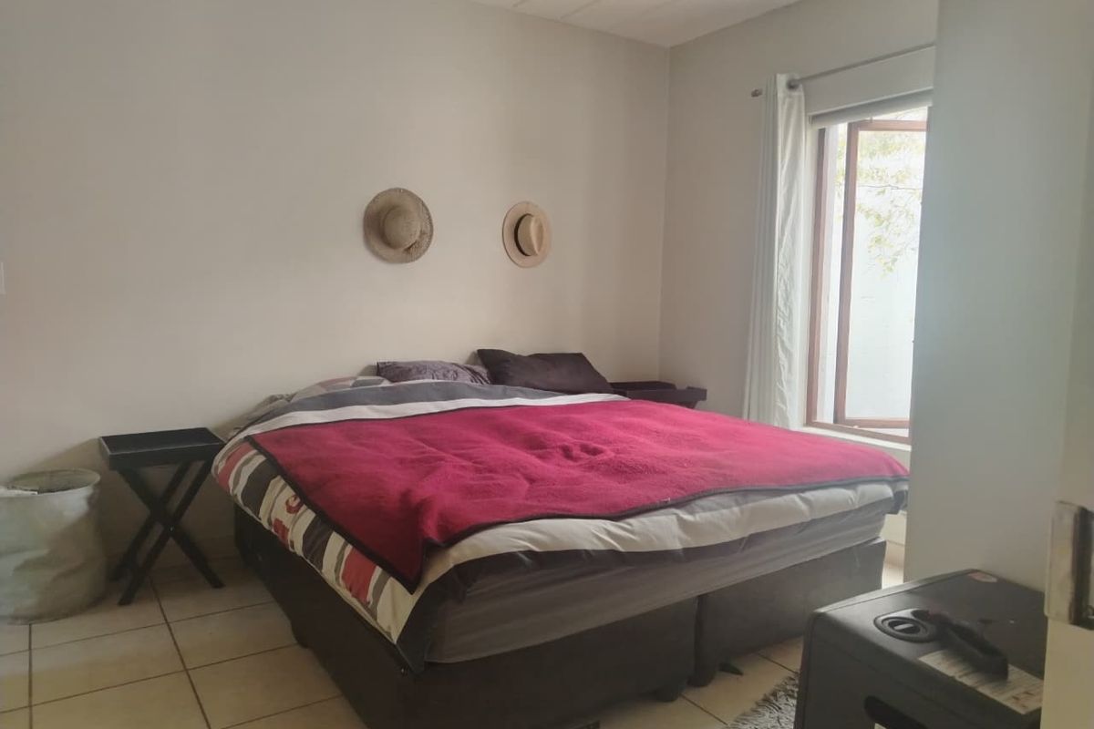 A functional bedroom featuring tiled flooring and a window providing natural light, offering a neutral base for potential interior updates.