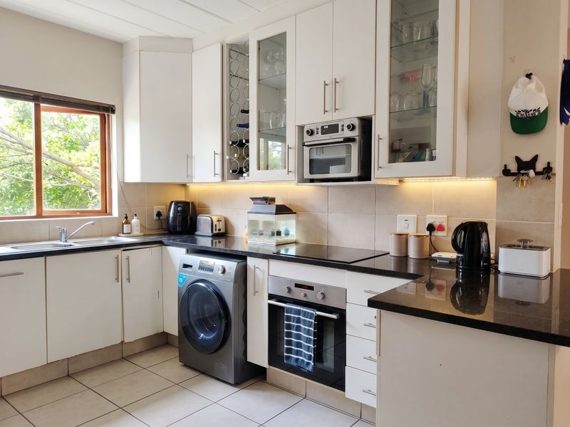 A well-maintained kitchen featuring white cabinetry, granite countertops, integrated oven and microwave, and under-cabinet lighting with a view of the outdoors.