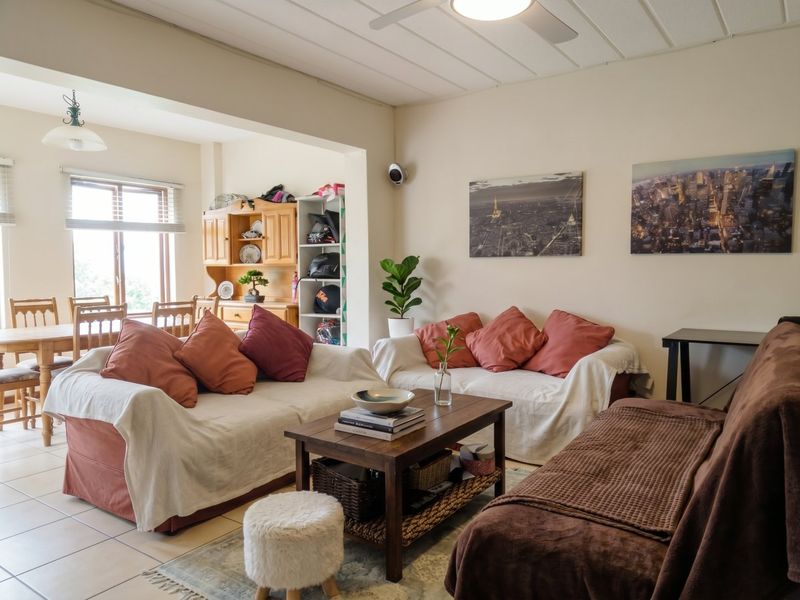 Spacious open-plan living and dining area featuring tiled flooring, neutral walls, and ample natural light from large windows.