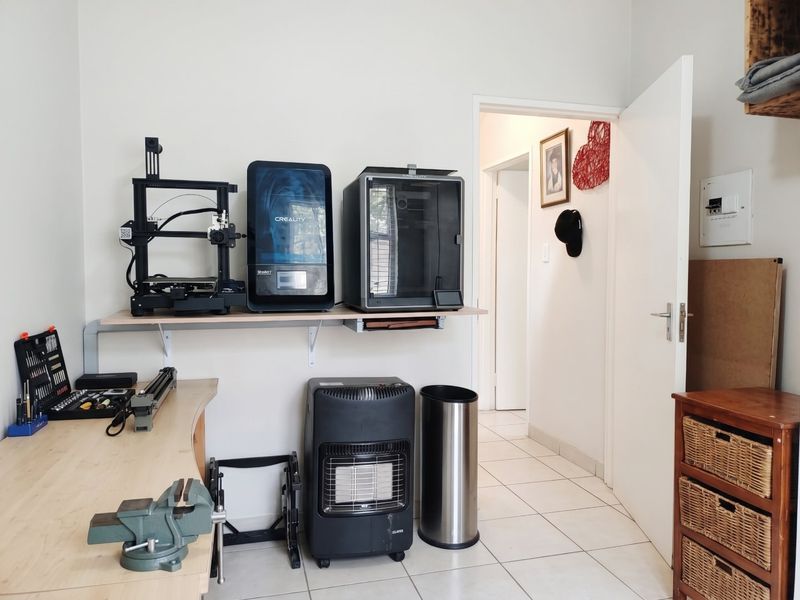 A functional workspace featuring wall-mounted shelving, tiled flooring, and an integrated electrical distribution board, suitable for a home office or hobby room.