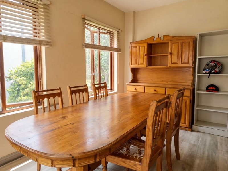 A dining room featuring timber window frames, venetian blinds, and laminate flooring, offering a functional space with natural light.