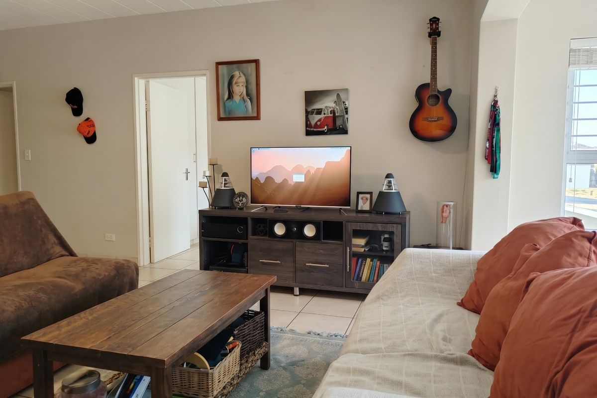 A comfortable living room featuring tiled flooring and a textured ceiling, providing a functional and neutral space for relaxation.