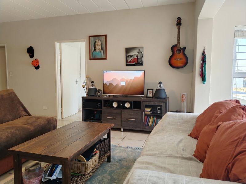 A comfortable living room featuring tiled flooring and a textured ceiling, providing a functional and neutral space for relaxation.