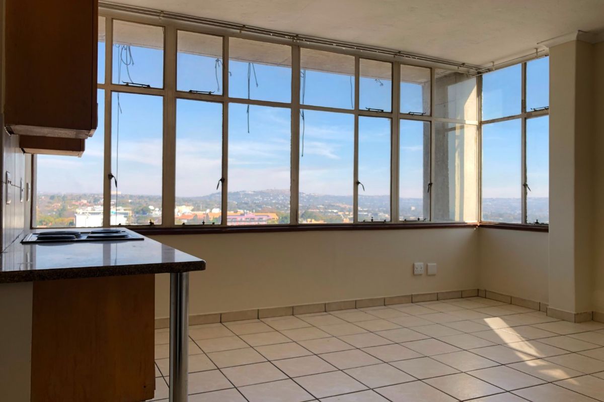 An empty kitchen area featuring tiled floors, built-in cabinetry, and expansive windows offering panoramic city views.