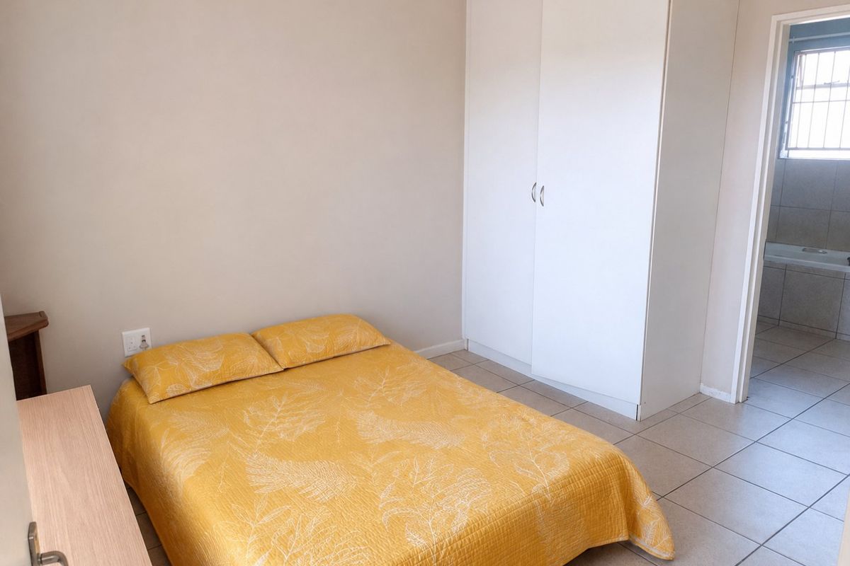 A functional bedroom featuring tiled flooring, a built-in wardrobe, and direct access to an adjoining bathroom.