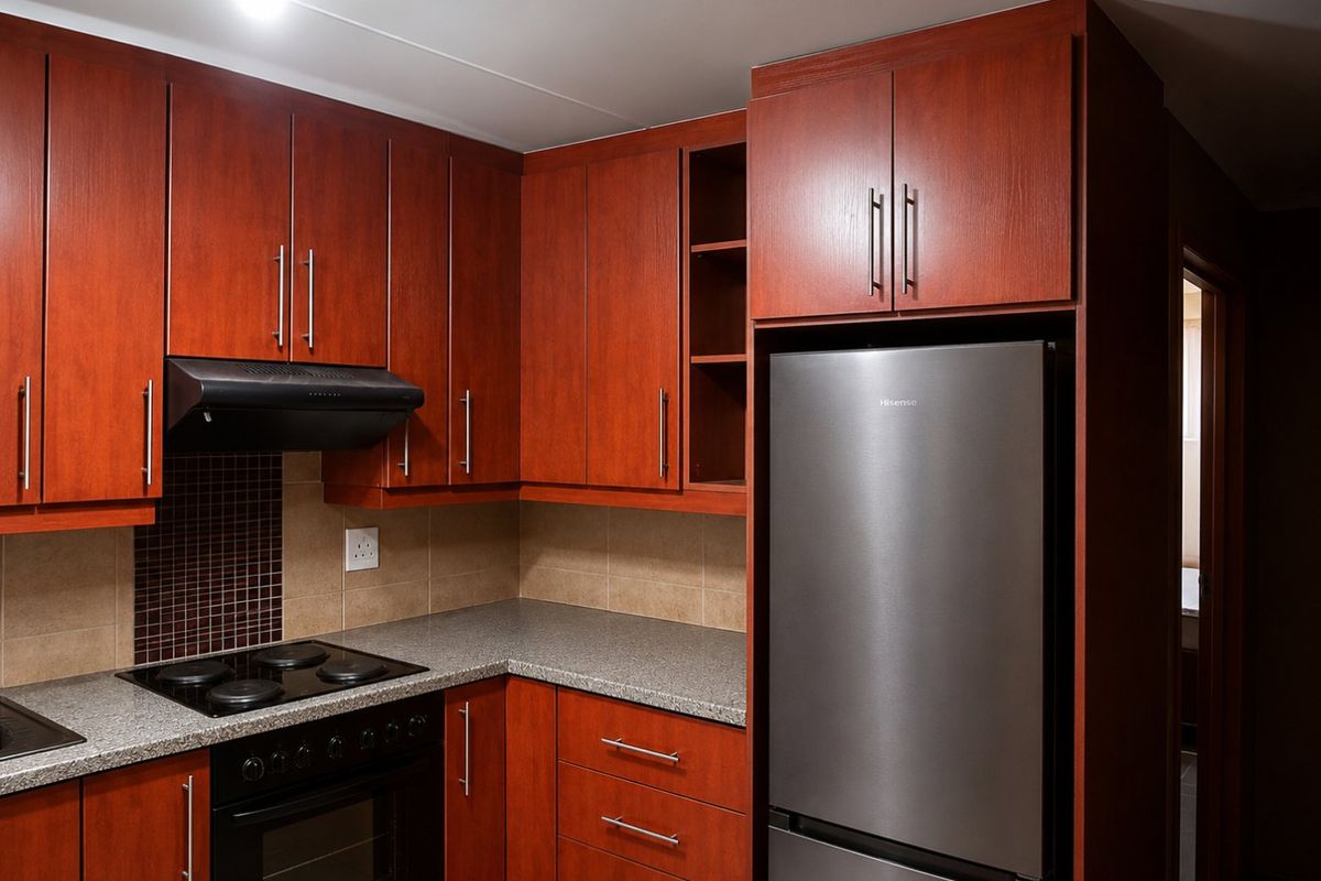 A functional kitchen featuring dark wood-finish cabinetry, granite-look laminate countertops, a tiled backsplash, and integrated cooking appliances.