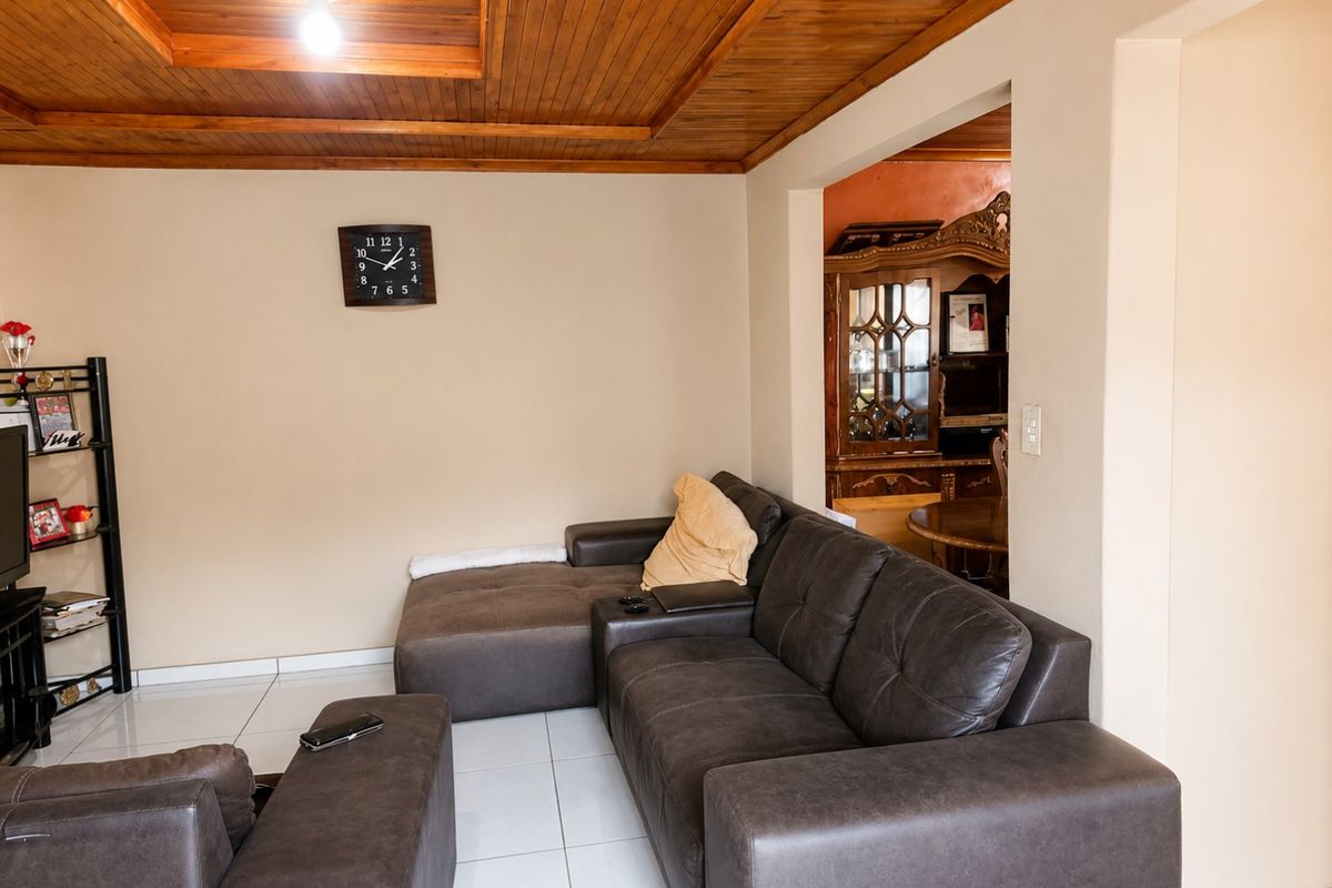 Living room featuring a warm timber tongue and groove ceiling with recessed detail and neutral ceramic floor tiles.
