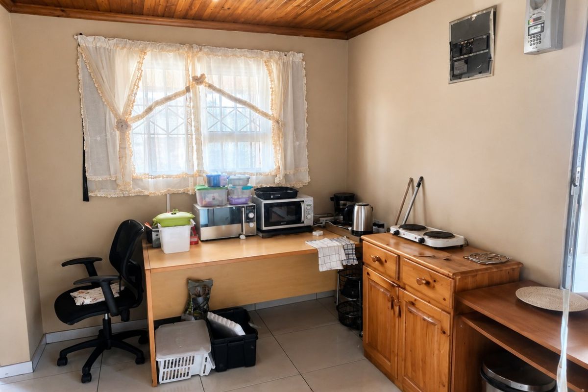 A functional kitchen area featuring tiled flooring, a timber tongue and groove ceiling, and a window fitted with a security gate.