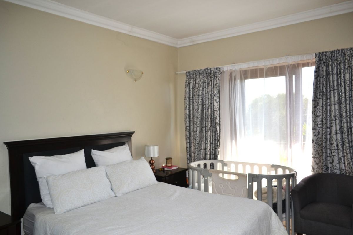 A well-lit bedroom featuring crown molding, a wall sconce, and a large sliding glass door providing natural light.