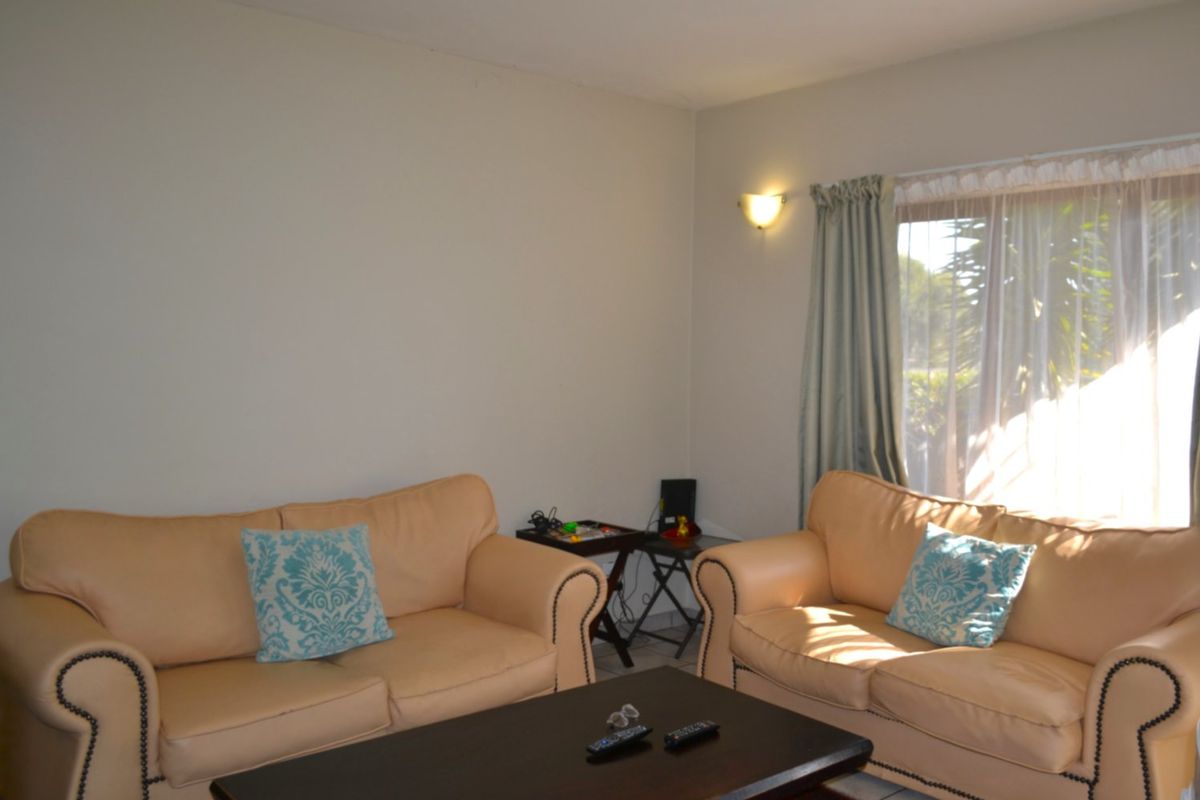 A comfortable living room area featuring neutral wall finishes and natural light through a window with curtain tracks.