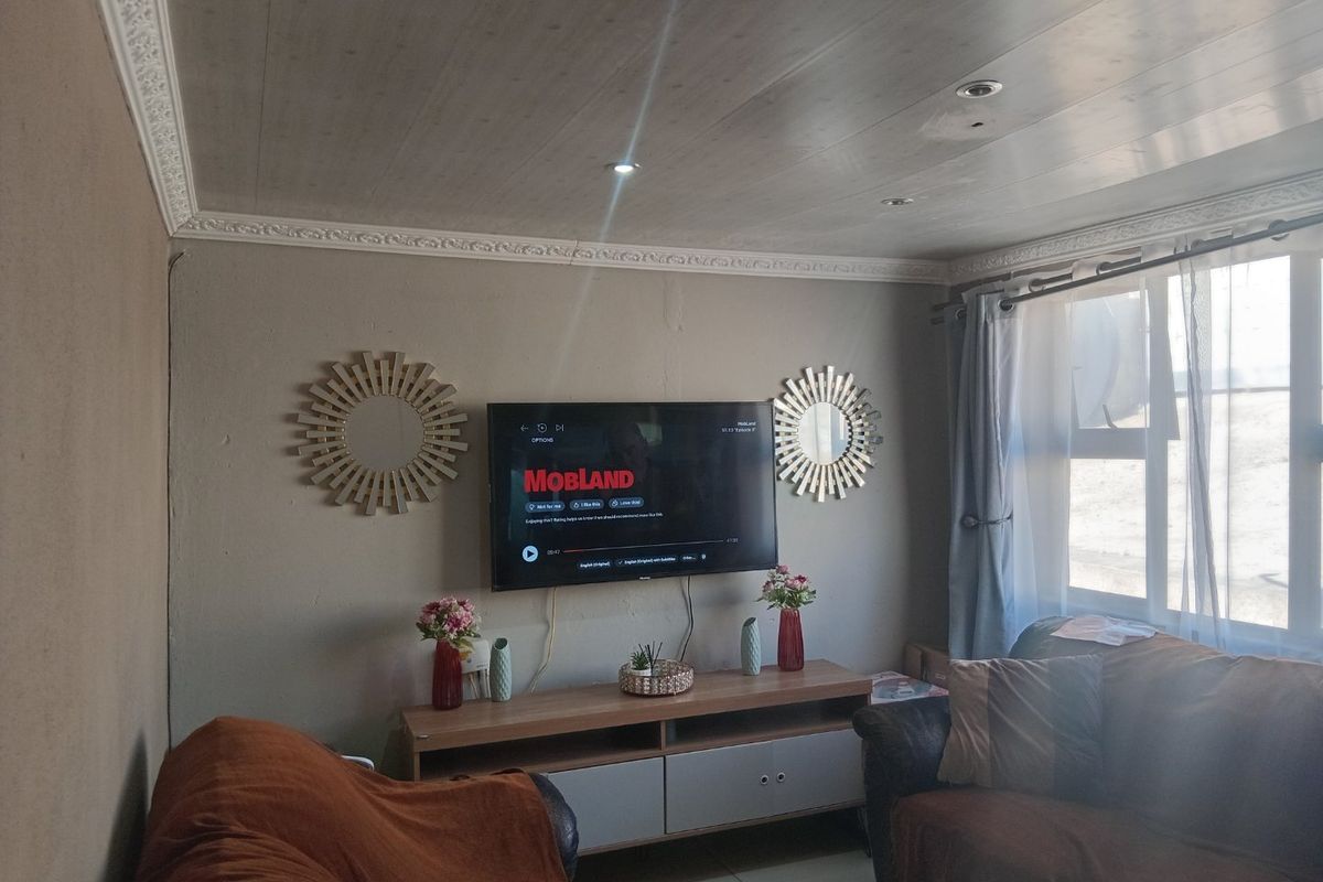 A living room featuring tiled flooring, recessed downlights, and decorative ceiling cornicing, providing a functional space for relaxation.