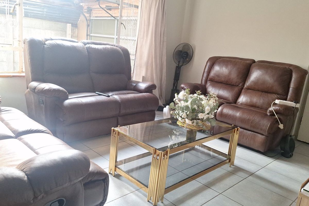 A living room featuring tiled flooring and a large window with security bars, providing natural light to the space.
