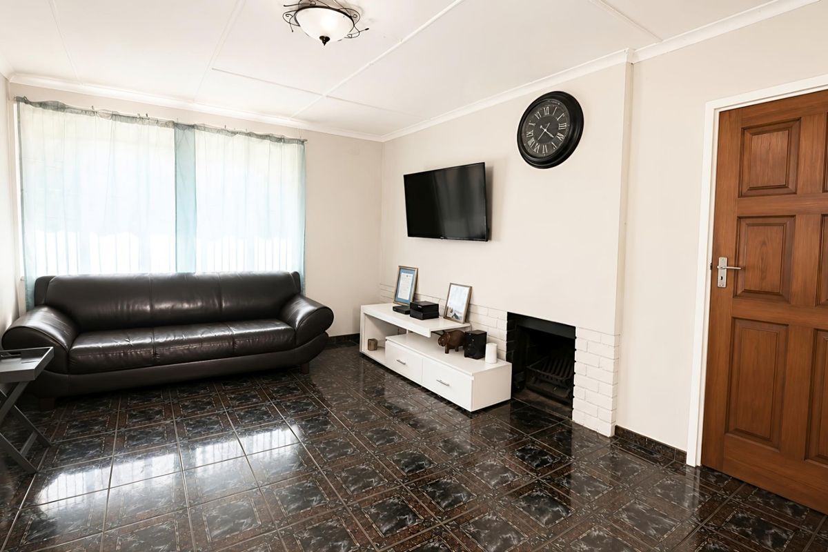 A living room featuring dark tiled flooring, a built-in fireplace with a white brick surround, and a solid timber door.