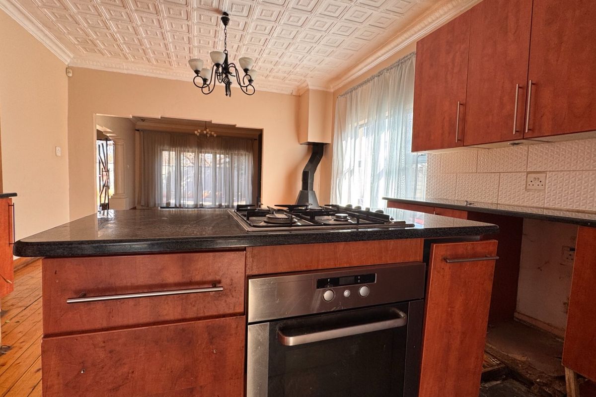 Kitchen featuring a central island with built-in oven and gas hob, granite countertops, and a decorative coffered ceiling.