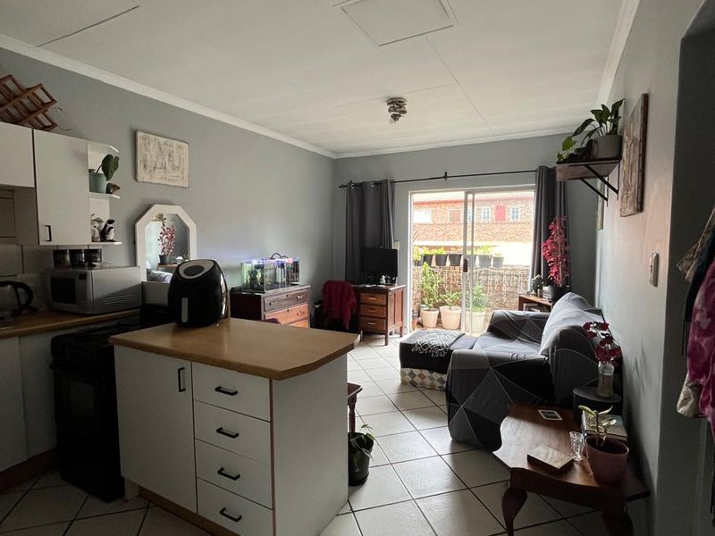 Open-plan living area featuring a kitchen with island, tiled flooring, and sliding door access to an outdoor space.
