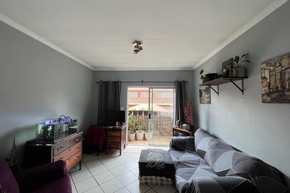 A living room featuring tiled flooring and a sliding glass door providing access to an outdoor patio area.