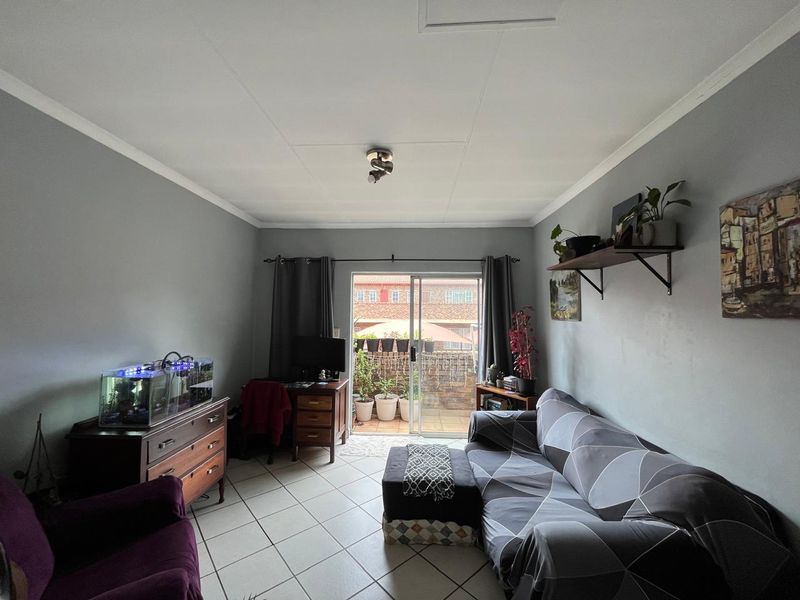 A living room featuring tiled flooring and a sliding glass door providing access to an outdoor patio area.