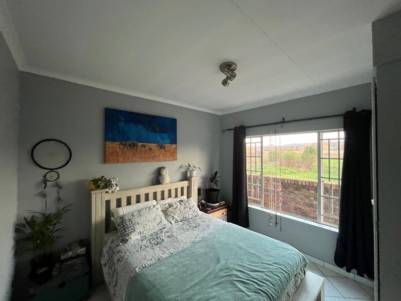 A bedroom featuring tiled flooring, a ceiling-mounted spotlight, and a window with views of the exterior.