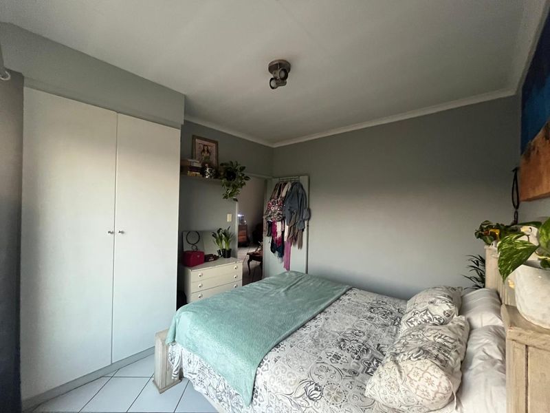 A bedroom featuring built-in wardrobes, tiled flooring, and neutral wall finishes, offering a functional space with potential for modern updates.