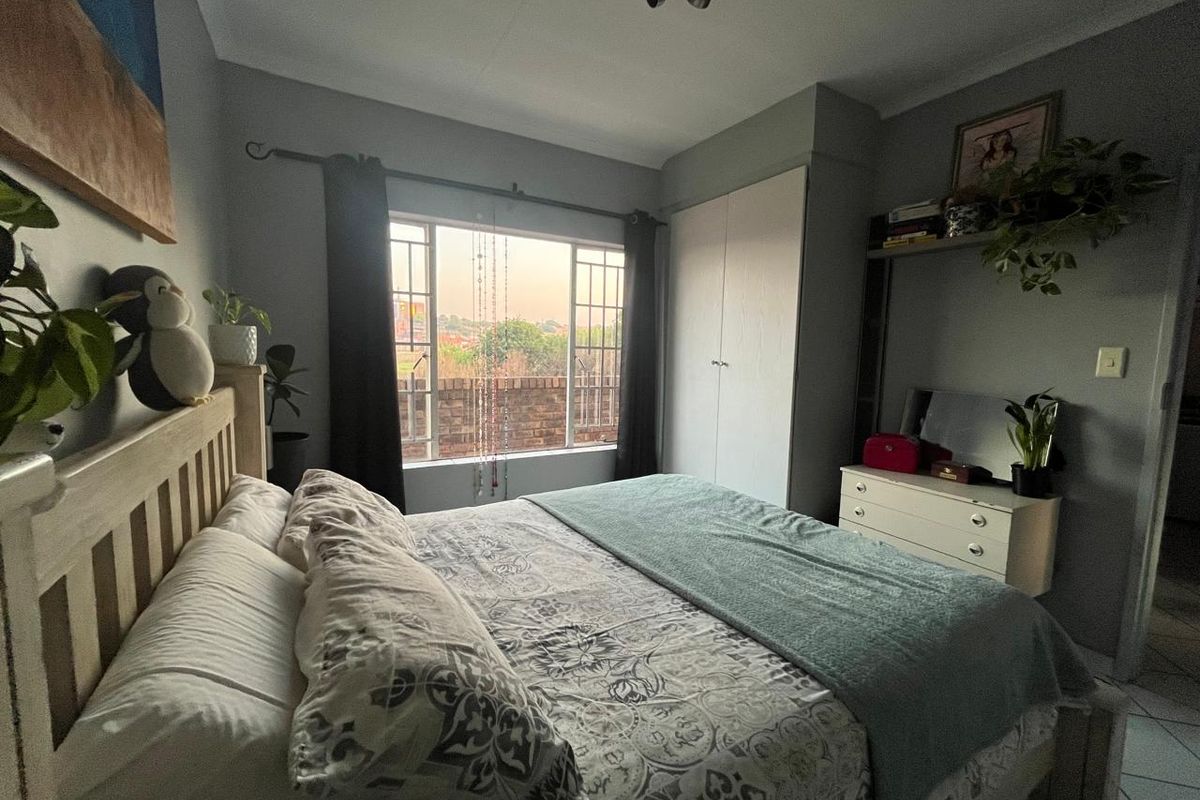 A cozy bedroom featuring a built-in wardrobe, a window with natural light, and a ceiling light fixture.