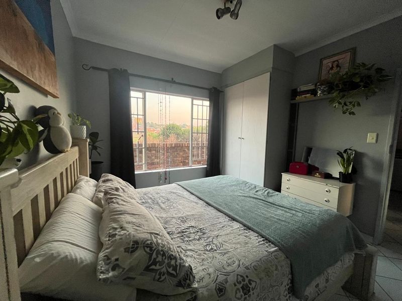 A cozy bedroom featuring a built-in wardrobe, a window with natural light, and a ceiling light fixture.
