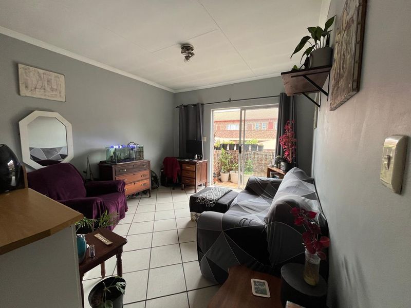 A living room featuring tiled flooring and a sliding glass door providing access to an outdoor patio area.