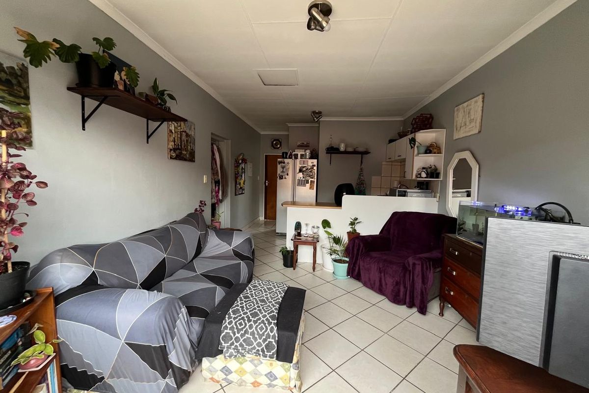 Open plan living area featuring tiled flooring and a breakfast bar connecting to the kitchen space.